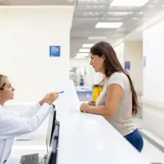 Rejestratorka medyczna wyjaśnia pacjentce dokumenty. Ciekawe, ile zarabia rejestratorka medyczna w porównaniu do innych zawodów medycznych.