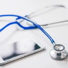 Biały smartfon i niebieski stetoskop leżą obok siebie. To narzędzia, które mogą pomóc każdemu serwisantowi w diagnozowaniu problemów.