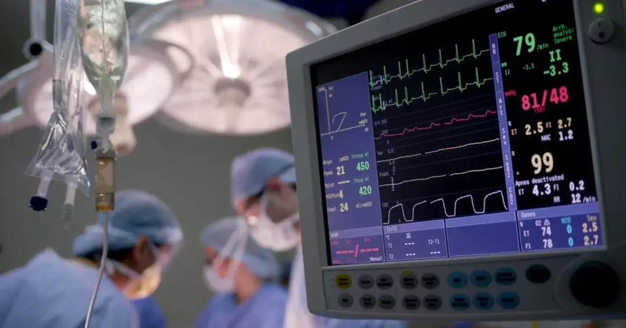 Monitor EKG na sali operacyjnej, gdzie pracują anestezjolodzy. W tle kroplówka i światła. Warto wiedzieć, ile zarabia anestezjolog.